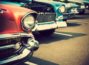 Several older classic cars parked in a row